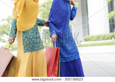 Female Friends In Muslim Dresses Walking Outdoors With Paper-bags After Shopping