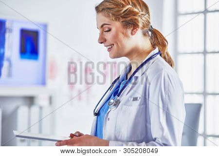 Young Woman Doctor Is Standing With Board With Clipboard Smilin