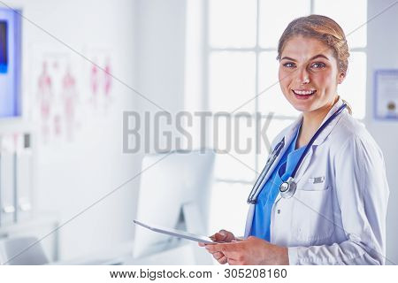Young Woman Doctor Is Standing With Board With Clipboard Smilin