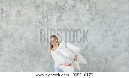 Housewife Choice. Happy Lady Holding Feather Pillow Pile. Gray Wall Background. Copy Space.