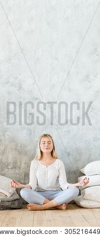 Morning Meditation. Woman Sitting On Floor Cross Legged In Yoga Pose With Mudra Hands. Gray Wall Bac