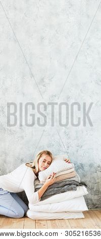 Natural Home Textile. Woman Enjoying Rest On Pile Of Cozy Pillows. Gray Wall Background. Copy Space.