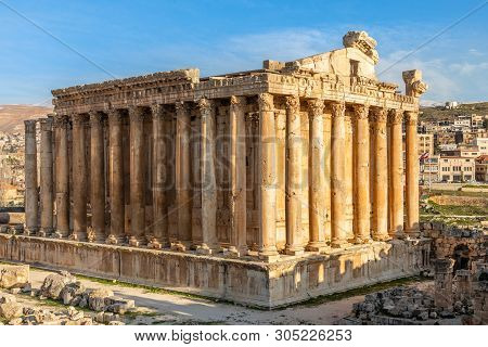 Columns Of Ancient Roman Temple Of Bacchus With Surrounding Ruins And Blue Sky In The Background, Be