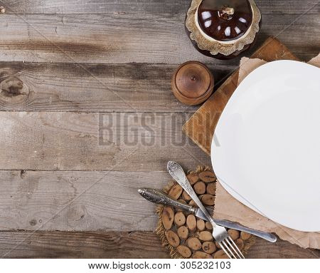 Light Empty Plate With Kitchen Accessories On A Wooden Background In Vintage Style.