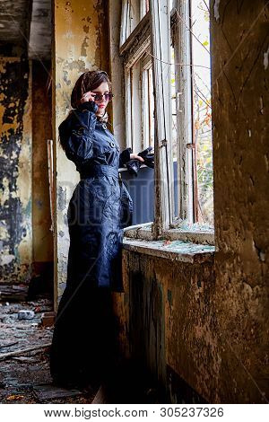Girl In A Black Cloak, A Scarf And A Diplomat In An Abandoned House Near Window. A Spy In A Secret M