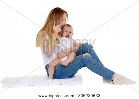 Young mother with unhappy crying baby  sit on a white background. Nursing and parenting. Eight months