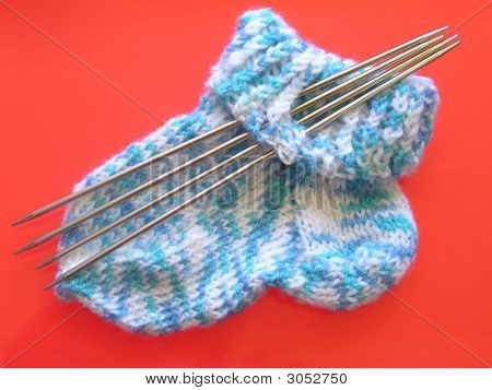 Gestrickte Socke und Nadeln auf rot