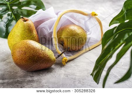 Fresh Pears In A Mesh Bag On Stone Background With Green Monstera Leaves. Zero Waste, Less Plastic C