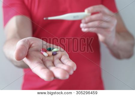A Man With A Thermometer In His Hand. Elevated Body Temperature. Cold And Flu Pills. Prevention And 