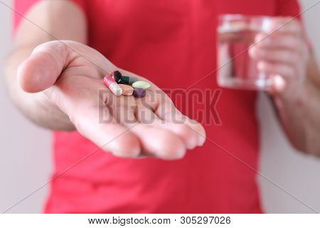 A Man With A Glass Of Water In His Hand. Elevated Body Temperature. Cold And Flu Pills. Prevention A