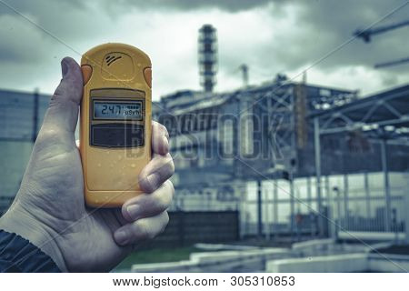 radiometer in hand with fourth Chernobyl Nuclear Power Plant reactor on the background