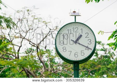 The Green Clock In The Park Is Powered By The Sun.