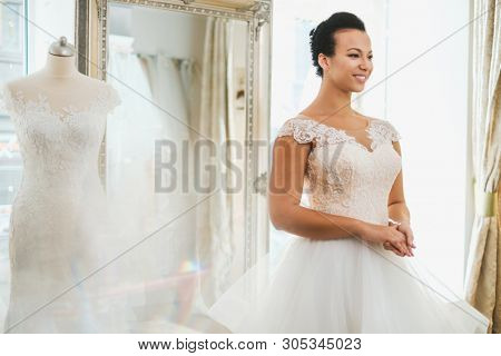 Beautifu bride choosing wedding dress in a wedding salon