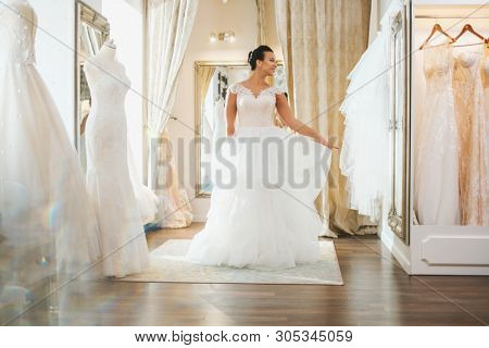 Beautifu bride choosing wedding dress in a wedding salon