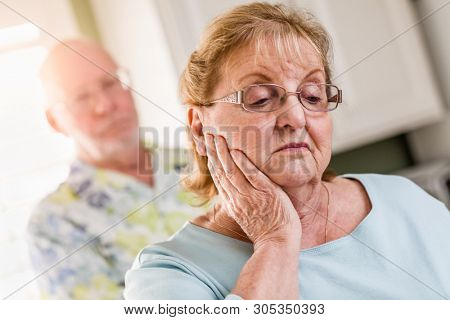 Senior Adult Man Standing Behind Sad Senior Adult Female.