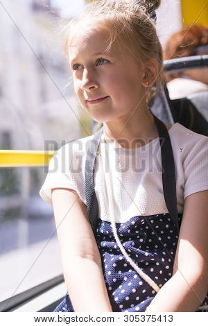 A Little Girl Is Going By Bus. Schoolgirl Sitting In School Bus And Ready For Her First Ride. Vertic