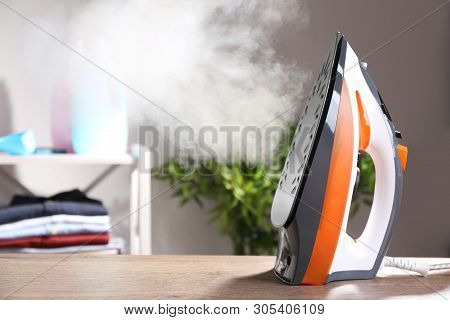 Modern Iron With Steam On Table Indoors. Space For Text