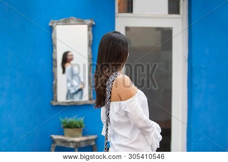 Beautiful Woman On White Dress Looking At Herself On A Mirror On The Colorful Streets Of The Colonia