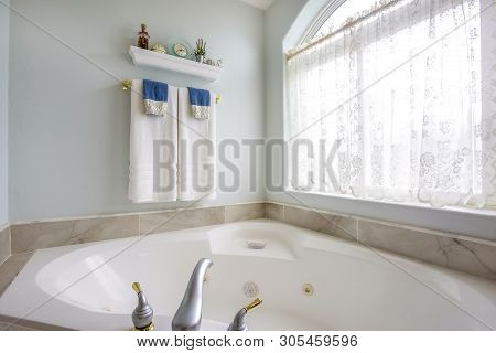 Bathroom Interior With Agleaming Bathtub Beside A Large Arched Window