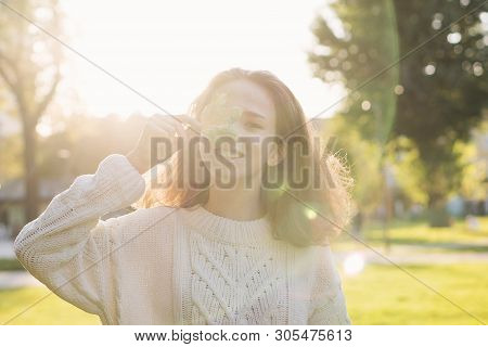 Portrait Of European Charming Teen Girl With A Maple Leaf In Hands. She Poses In Rays Of Sunset And 