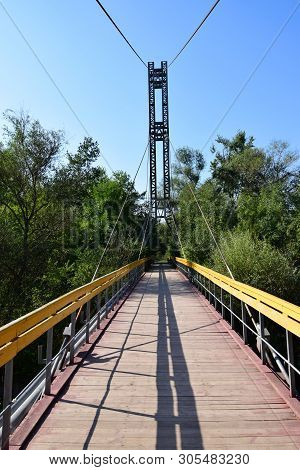 Suspension Bridge With Yellow Railings And Taut Cables Across The River On Mount Kizilovka In The Fo