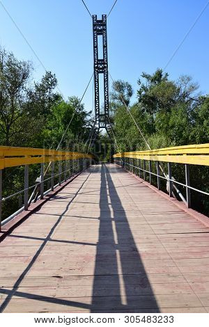 Mountain Suspension Bridge With Yellow Railings And Taut Cables Across The River On Mount Kizilovka 