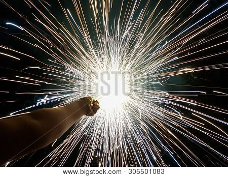 Hand Charki, A Hand Firework Emitting Circular Sparks In Black Background