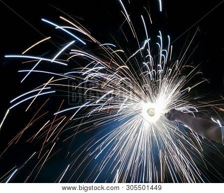 Hand Charki, A Hand Firework Emitting Circular Sparks In Black Background