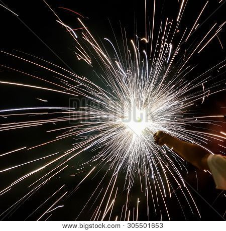 Hand Charki, A Hand Firework Emitting Circular Sparks In Black Background