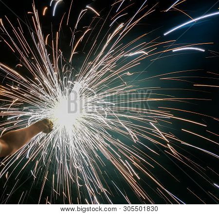 Hand Charki, A Hand Firework Emitting Circular Sparks In Black Background