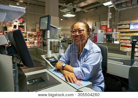 ZURICH, SWITZERLAND - CIRCA OCTOBER, 2018: indoor portrait of a retail cashier at Coop grocery store in Zurich.
