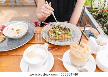 Traditional Belgian Waffle With Salmon, Lettuce Leaves And Poached Egg. A Young Woman Is Having Brea
