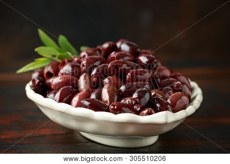 Pitted Kalamata Olives In Bowl On Rustic Wooden Background