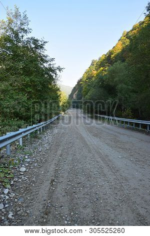 View Of The Mountain Road With Railings Through The Forest In Cherek Gorge In The Mountains Of The N