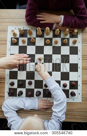 Hand Of Teacher Above Chess Board Preventing Boy From Making Wrong, Thoughtless Chess Move