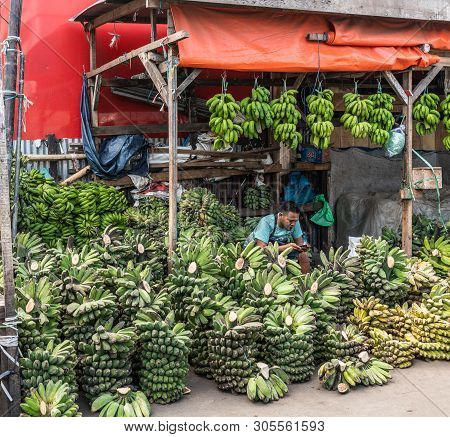 Makassar, Sulawesi, Indonesia - February 28, 2019: Terong Street Market. Banana Vendor Reads Smart P