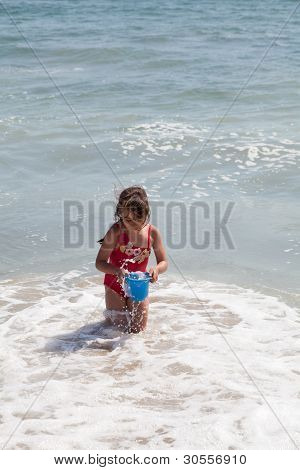 Bambina giocando con un secchio sulla spiaggia