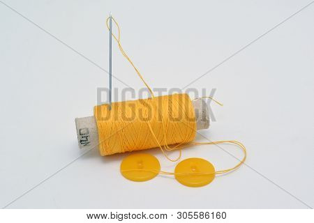 Yellow Thread With Needle And Yellow Buttons.