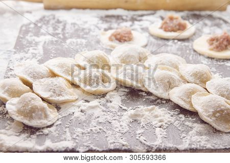 Raw Yellow Dumplings, Flouted Lie On Wooden Brown Board In A Semicircle