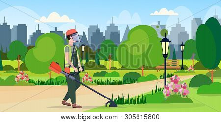 Man Gardener In Uniform Cutting Grass With Brush Cutter Gardening Concept Urban City Park Cityscape 