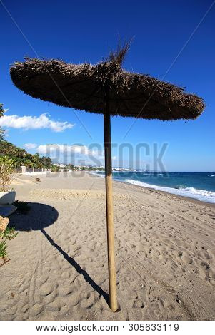 Single Raffia Parasol On Daitona Beach With Views Along The Coastline, Marbella, Costa Del Sol, Mala