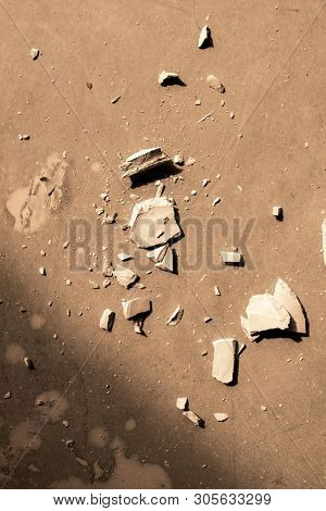 Overview of smithereens of broken clay item on flat brown surface that can be used as background