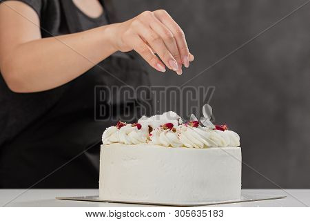 The Condater Sprinkles The Cake With Grated Almonds And Coconut. Close-up Of A Hand And Pouring Crum