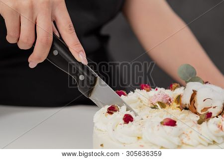 A Condater Cuts A Beautiful Fresh Decorated White Cake With A Large Knife.