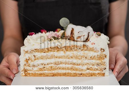 Half A Cake. Close-up Of A Cut Cake With Visible Layers And Filling. Onditer Holds The Cake In His H