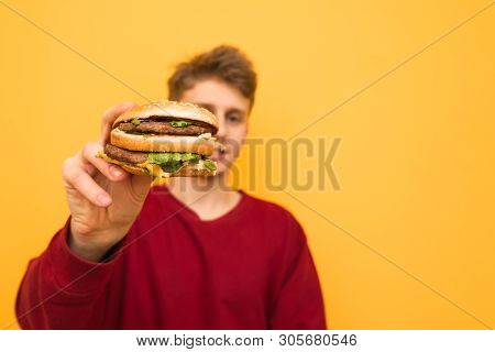 Background. Close-up Of A Burger In The Hands Of A Young Man. Guy Holds In His Hands A Quick Harmful
