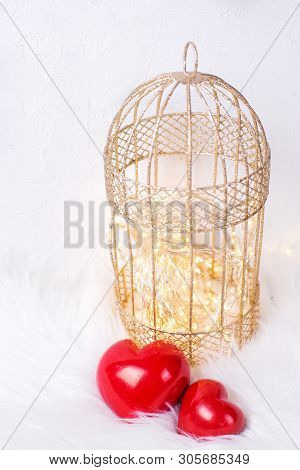 Valentines Day  Concept. Two Decorative Hearts,  Golden Cage With Firy Lights  On  White  Fur Backgr