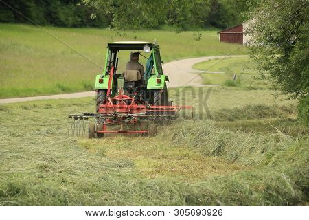 Farmer With Tractor And Hay Tedder At The Hay Harvest