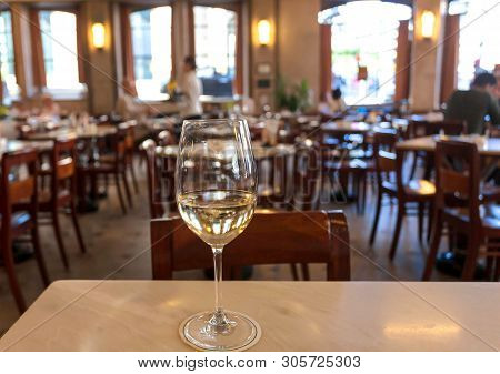 Some People Drinking White Wine Inside Light Huge Restaurant In Retro Style. Leisure Concept.