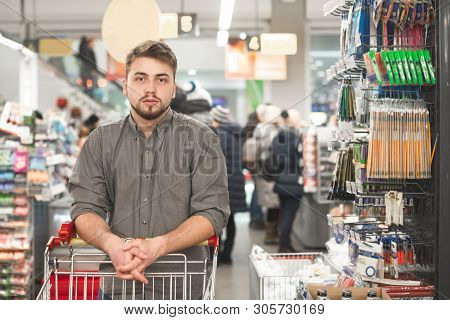 At The Supermarket: Handsome Man Uses Smartphone And Looks At Nutritional Value Of The Canned Goods.
